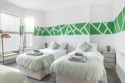 a bedroom with two beds and a green and white wall at Contractor Luxury Home - Long Stays - 4 Bedrooms - Sleep 8 - Zip & Link Beds - Ultra Fast WiFi - Free Parking in Birkenhead