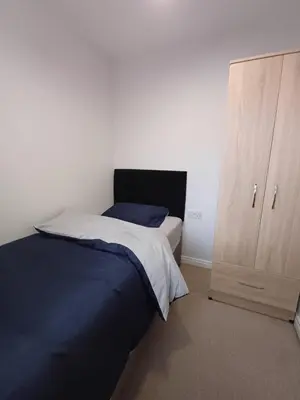 a bedroom with a bed and a wooden cabinet at Great Home in Liverpool