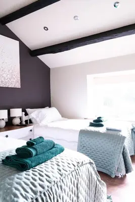 a bedroom with two beds with green towels on them at Luxury modern canal side cottage for families, couples, contractors and dog friendly in Lancashire sleeps 6 in Preston