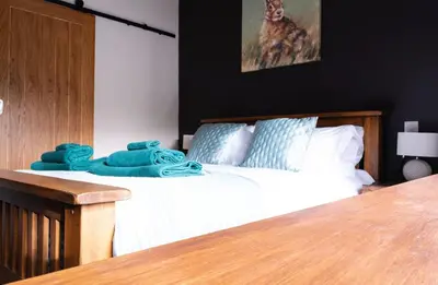 a bedroom with a bed with white sheets and blue pillows at Luxury modern canal side cottage for families, couples, contractors and dog friendly in Lancashire sleeps 6 in Preston