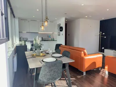 a kitchen and dining room with a table and orange chair at Balcony 60 Inch TV Penthouse City Centre with views in Liverpool