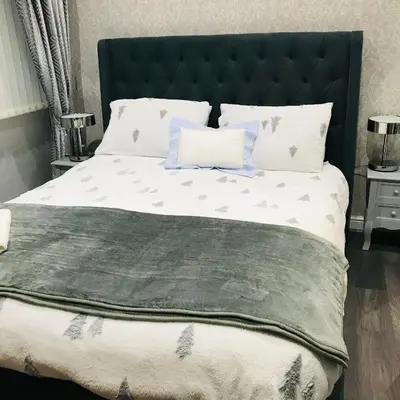 a bedroom with a large bed with a black headboard at Sefton Cottage in Ormskirk