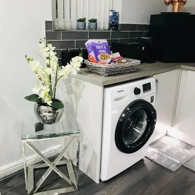 a white washing machine sitting next to a table at Sefton Cottage in Ormskirk