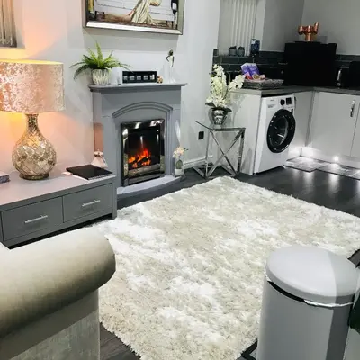 a living room with a fireplace and a white rug at Sefton Cottage in Ormskirk