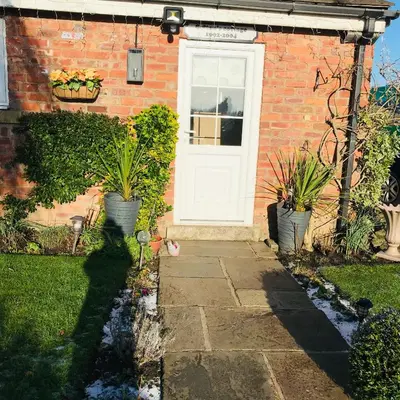 a brick house with a white door and two potted plants at Sefton Cottage in Ormskirk