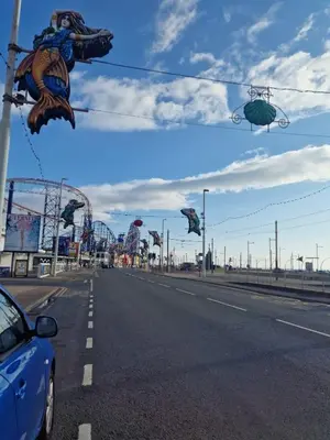a car driving down a road with a roller coaster at Delightful Blackpool Home in Blackpool