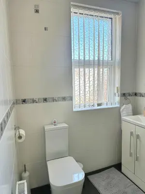 a white bathroom with a toilet and a window at Delightful Blackpool Home in Blackpool