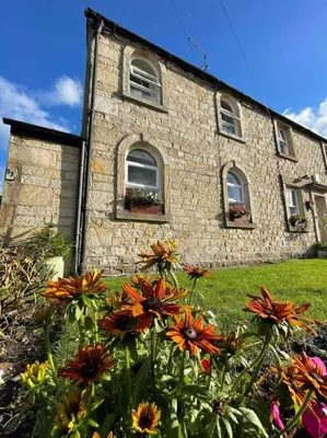 a stone building with flowers in front of it at Cottage Apartment Near Lancaster University in Galgate