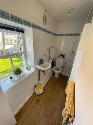 a bathroom with a toilet and a sink and a window at Cottage Apartment Near Lancaster University in Galgate