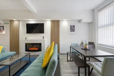 a living room with a couch and a table and a fireplace at Burnand House - Air Host & Stay - Sleeps 9 in Liverpool