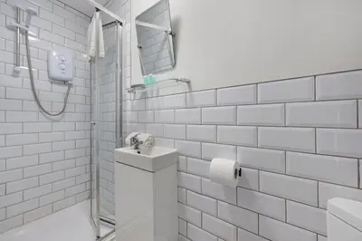 a white tiled bathroom with a sink and a shower at Burnand House - Air Host & Stay - Sleeps 9 in Liverpool