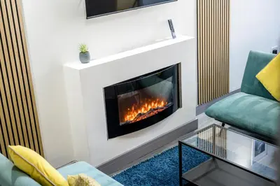 a living room with a fireplace and a green couch at Burnand House - Air Host & Stay - Sleeps 9 in Liverpool