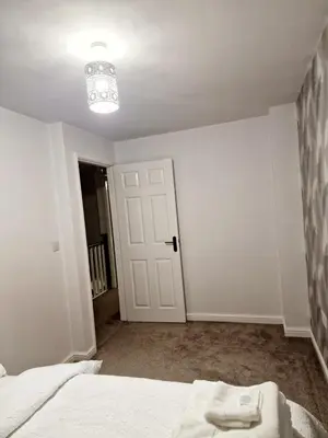 a white room with a bed and a chandelier at Entire 3 bedroom luxurious house, Wigan , Manchester in Wigan