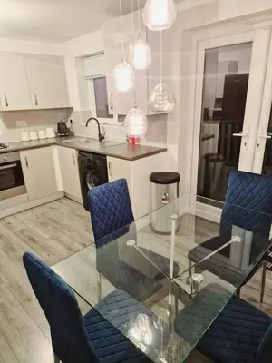 a kitchen with a glass table and blue chairs at Entire 3 bedroom luxurious house, Wigan , Manchester in Wigan