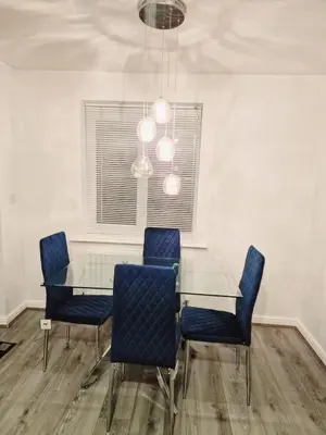 a dining room with a glass table and blue chairs at Entire 3 bedroom luxurious house, Wigan , Manchester in Wigan