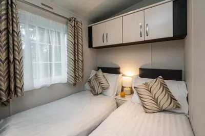two beds in a small bedroom with a window at Stylish and cozy holiday home in Carnforth