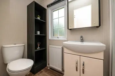 a bathroom with a sink and a toilet and a window at Stylish and cozy holiday home in Carnforth