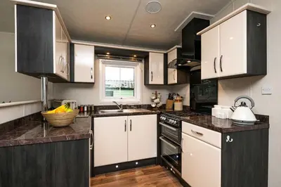 a kitchen with white cabinets and black counter tops at Stylish and cozy holiday home in Carnforth