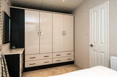 a bedroom with a large white cabinet and a bed at Stylish and cozy holiday home in Carnforth
