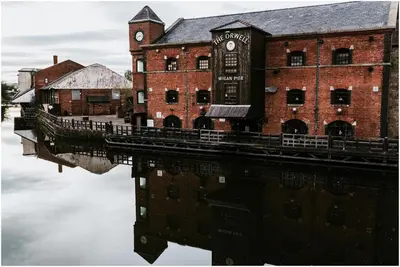 a building with a clock tower next to a body of water at Cosy Central 2-Bed Flat City View & Parking in Wigan