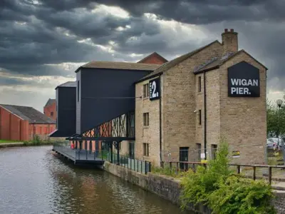 a building with a sign on it next to a river at Cosy Central 2-Bed Flat City View & Parking in Wigan