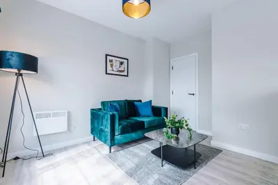 a living room with a green couch and a table at Elysée Suites - Stylish 1 Bed Flat in Southport in Southport
