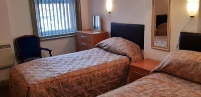 a hotel room with two beds and a mirror at Oakville Apartments in Blackpool