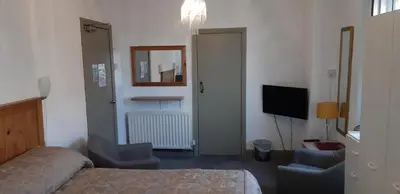 a bedroom with a bed and two chairs and a television at Oakville Apartments in Blackpool