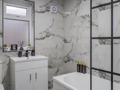 a white bathroom with a tub and a sink at West Park House in Penwortham
