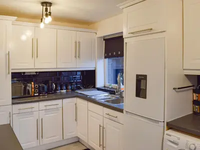 a kitchen with white cabinets and a white refrigerator at West Park House in Penwortham