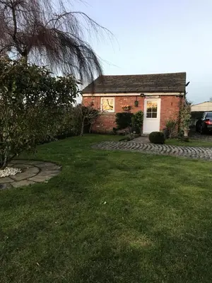 a small brick house with a grass yard at Sefton Cottage in Ormskirk