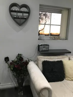 a living room with a couch and a heart mirror at Sefton Cottage in Ormskirk