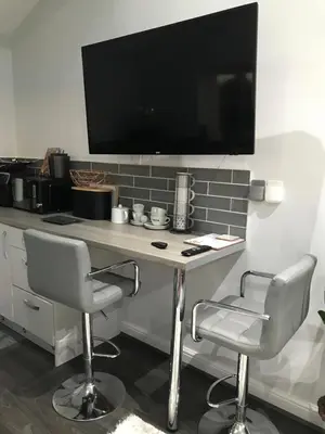a desk with two chairs and a television on a wall at Sefton Cottage in Ormskirk