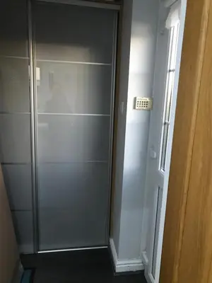 a walk in closet with a glass shower door at Sefton Cottage in Ormskirk