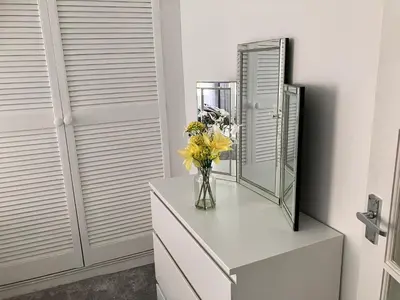 a vase of flowers on a dresser next to a mirror at 2 Bedroom Beachside House Sleeps 4 - Private Patio in Southport