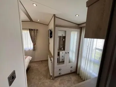 a bedroom with a mirror and a dresser with a television at Lakeside location, sleeps 8, 3 bedrooms, fully glazed wrap around decking, Haven Lakeland, Lake District in Flookburgh