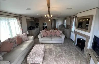 a living room with two couches and a kitchen at Lakeside location, sleeps 8, 3 bedrooms, fully glazed wrap around decking, Haven Lakeland, Lake District in Flookburgh
