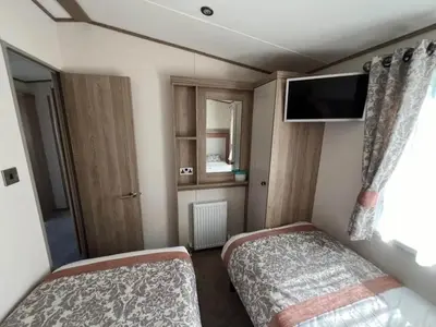 a small room with two beds and a tv at Lakeside location, sleeps 8, 3 bedrooms, fully glazed wrap around decking, Haven Lakeland, Lake District in Flookburgh