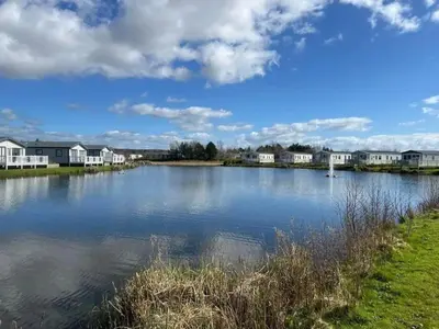 a large body of water with houses in the background at Lakeside location, sleeps 8, 3 bedrooms, fully glazed wrap around decking, Haven Lakeland, Lake District in Flookburgh
