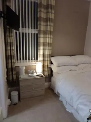 a bedroom with a bed and a night stand with a lamp at Nathans in Blackpool
