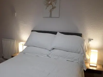 a bed with white pillows in a bedroom with two lights at Nathans in Blackpool
