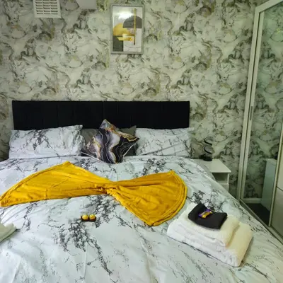 a bed with a yellow blanket and towels on it at West park Royal House, Holidays, Contractors,Relocation,Free Parking & WiFi in Preston
