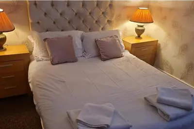 a bedroom with a large white bed with two lamps at 4 Bed House Sleeps 8 - Pet Friendly with Garden in Blackpool