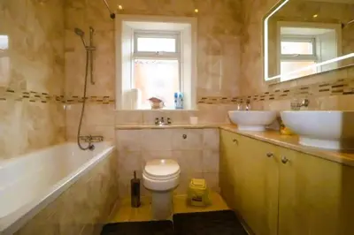 a bathroom with two sinks and a toilet and a tub at 4 Bed House Sleeps 8 - Pet Friendly with Garden in Blackpool