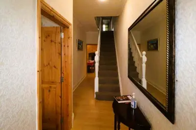 a hallway with a staircase and a mirror on the wall at 4 Bed House Sleeps 8 - Pet Friendly with Garden in Blackpool
