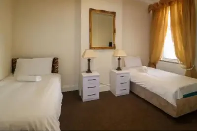 a bedroom with two beds and a mirror and a window at 4 Bed House Sleeps 8 - Pet Friendly with Garden in Blackpool