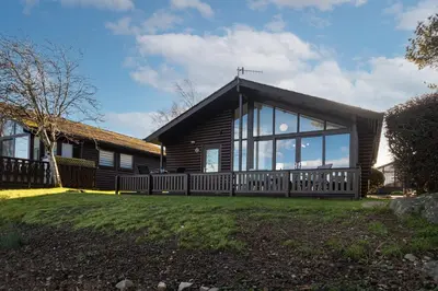 a log house with a large window at Sandmartin Lodge a lakeshore haven at Pine Lake Resort in Carnforth