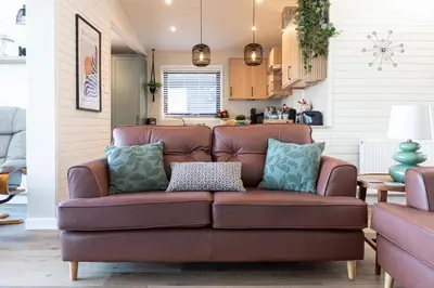 a brown leather couch in a living room at Sandmartin Lodge a lakeshore haven at Pine Lake Resort in Carnforth