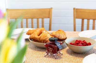 a table with a plate of pastries and a bowl of berries at Sandmartin Lodge a lakeshore haven at Pine Lake Resort in Carnforth