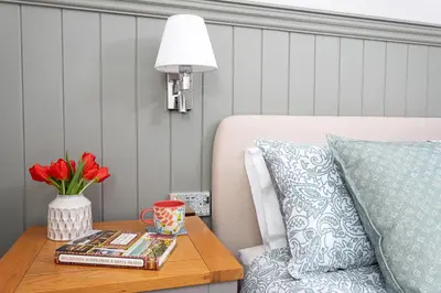 a table with a lamp and a vase of flowers on a table at Sandmartin Lodge a lakeshore haven at Pine Lake Resort in Carnforth